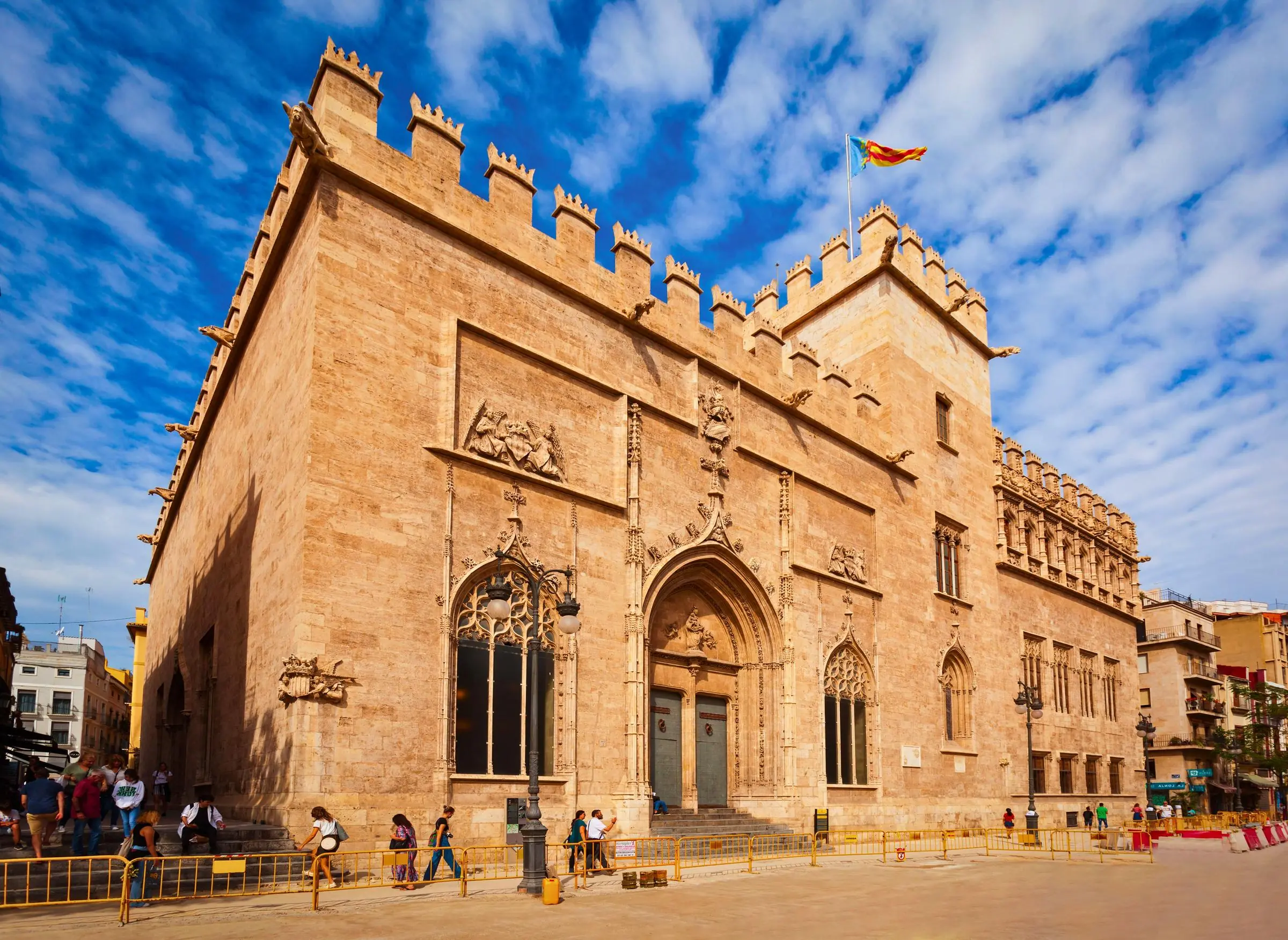 The fortress-like Gothic stone exterior of La Lonja de la Seda in Valencia, featuring crenellated battlements and arched windows